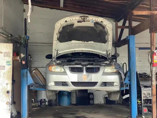 A silver BMW sedan on a two-post hydraulic lift for professional auto repairs in Tampa by BMW and More Auto Care LLC.