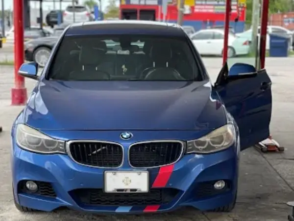 A blue BMW 3 Series sedan parked in a garage service bay for professional auto repairs in Temple Terrace, FL by BMW and More Auto Care.