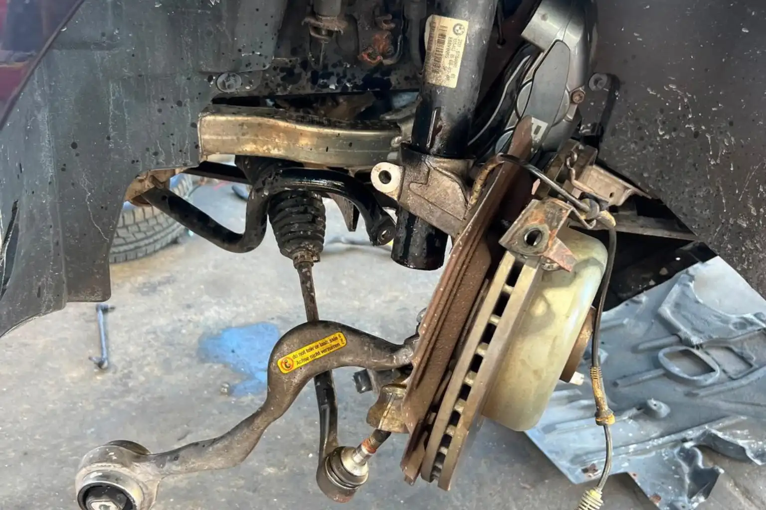Understanding car suspension systems by inspecting disconnected control arms, ball joints, and struts at BMW and More Auto Care LLC.
