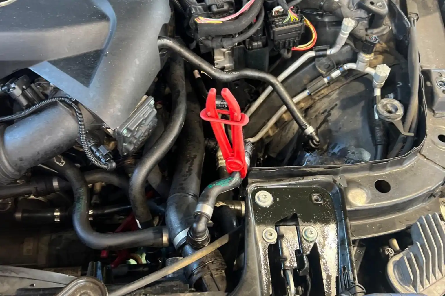 Preventing hidden dangers of coolant leaks triggering an engine temperature warning during a BMW engine bay inspection.